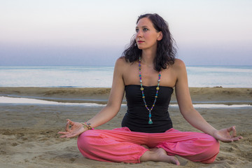 Fototapeta na wymiar Junge Frau zelebriert Yoga im sandigen Strand am Meer