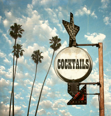 aged and worn vintage photo of cocktails sign and palm trees