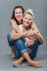 Two young cheerful sister hugging in the studio.