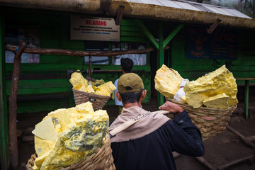 worker weighting sulfur for selling at Kawah Ijen volcano crater