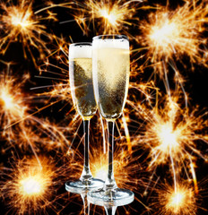Two glasses of champagne on bright background with sparklers