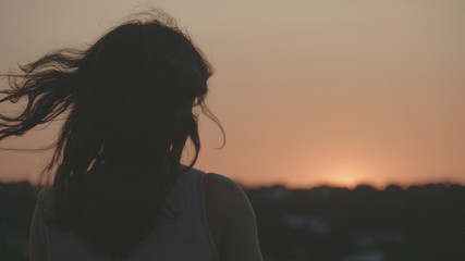 Silhouette of young lonely female watching sunset, sunrise. Beautiful pink sky