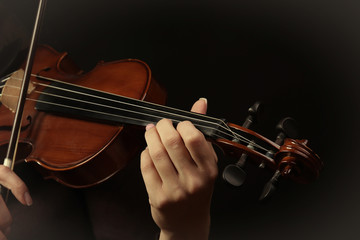 Fototapeta premium Violinist playing violin on dark background