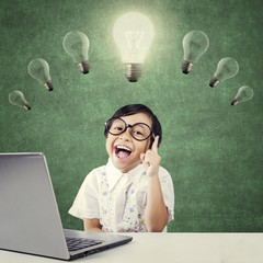 Smart kid sitting under lamp with laptop