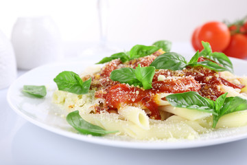 Pasta with tomato sauce and basil on table close up