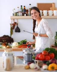 Young woman using a tablet computer to cook in her kitchen