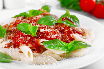 Pasta with tomato sauce and basil on table close up