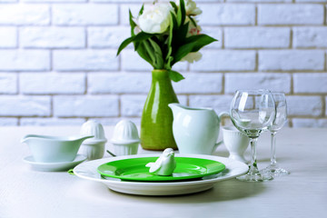 Beautiful table setting with flowers in vase on brick wall background