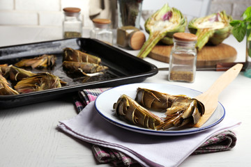 Roasted artichokes on plate, on kitchen table background