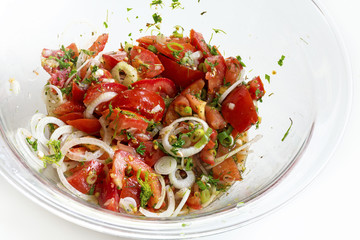 Tomato salad with onion rings and herbs in a glass bowl
