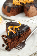 Piece of Cake with Chocolate Glaze and orange on plate, on wooden background