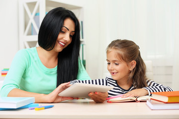 Beautiful school girl doing homework with mother at home