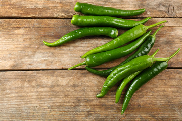 Green hot peppers on wooden table close up