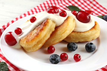 Fritters of cottage cheese with berries in plate, closeup
