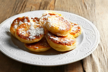 Fritters of cottage cheese in plate on wooden table, closeup