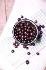 Red gooseberry in cup on wooden table close-up outdoors