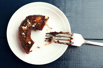 Piece of delicious doughnut with chocolate icing with fork on table close up