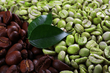 Green and brown coffee beans with leaves close up