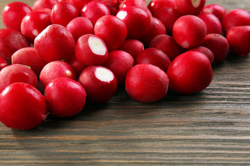 Heap of fresh radishes on wooden table close up background
