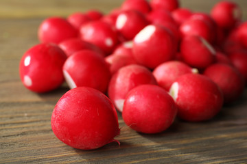 Heap of fresh radishes on wooden table close up background