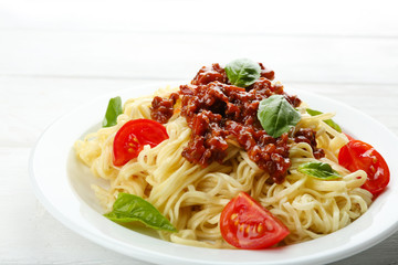 Spaghetti Bolognese on white plate, on color wooden background