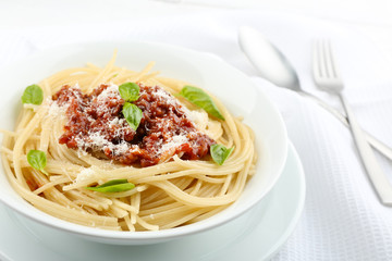 Spaghetti Bolognese with parmesan cheese in white bowl, on color wooden background