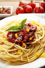 Spaghetti with tomato sauce, paprika and cheese on white plate, on color wooden background