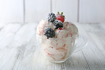 Delicious ice cream with fresh frozen berries, on color wooden background