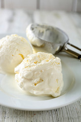 Delicious vanilla ice cream on plate, on wooden background