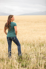 Naklejka na ściany i meble Young woman posing in wheat field.