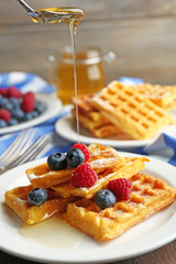 Sweet homemade waffles with forest berries and sauce on table background