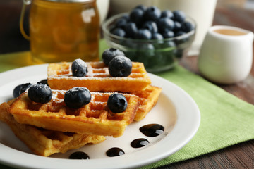 Sweet homemade waffles with forest berries and chocolate sauce on table background