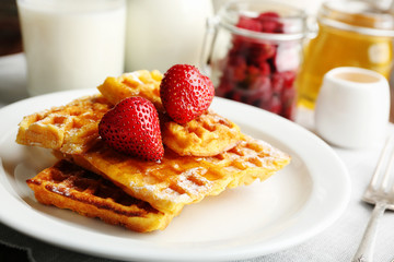 Sweet homemade waffles with strawberries  on plate, on table background