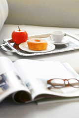 Light breakfast and magazines on sofa in living room, close up