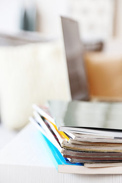 Magazines and laptop on table in living room, close up