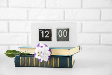 Modern Clock and books, on light wall background
