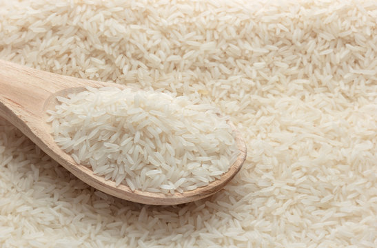 Close up jasmine rice with wooden spoon on rice background.
