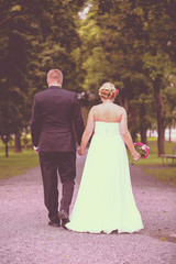 Just married. A newly weds walking towards a future together in the park. Image has vintage effect applied.