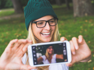 Blonde woman posing outdoor, taking self portrait