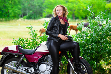 Fototapeta na wymiar Biker girl in leather jacket on a motorcycle