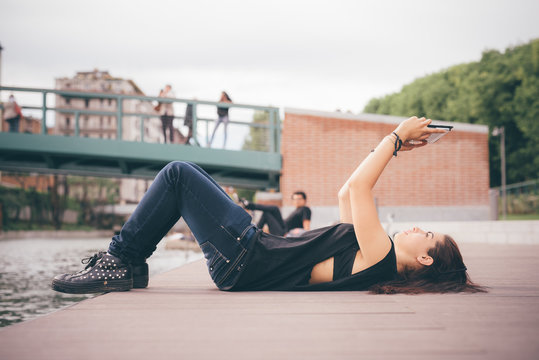 Side view of young woman using digital tablet while lying on boardwalk