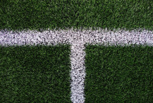 White line cross on green football field