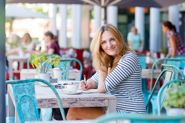 Woman drinking coffee and writing notes in cafe © Irina Schmidt