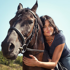 Obraz premium Portrait of beautiful young dark-haired woman on a horse.