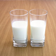 A fresh cold milk in high transparent glass. Let us eat cake with milk.

