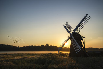 Fototapeta na wymiar Old windmill in foggy countryside landscape in England