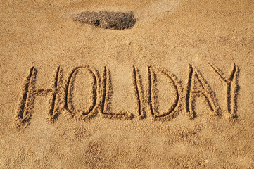 Fototapeta premium The word Holiday written in the sand on the beach