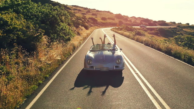 Happy Couple Driving on Country Road in Classic Vintage Sports Car 