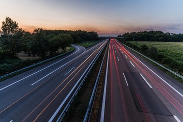 german highway at sunset with light trails from passing cars