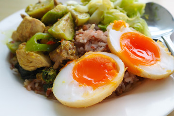 Soft-boiled eggs and green chicken curry with brown rice in dish
